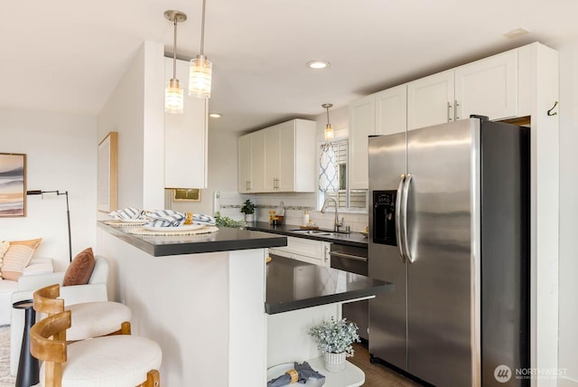 11515 Greenwood Ave N Unit C, Seattle, WA 98133 - kitchen with stainless steel fridge, a sink, dark countertops, a peninsula, and a kitchen bar