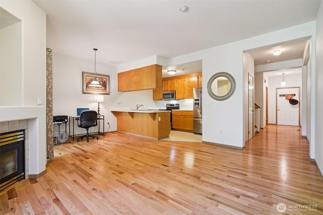 2419 S Meridian Unit B8, Puyallup, WA 98373 - kitchen with stainless steel appliances, a peninsula, a tile fireplace, light wood-style flooring, and a kitchen breakfast bar
