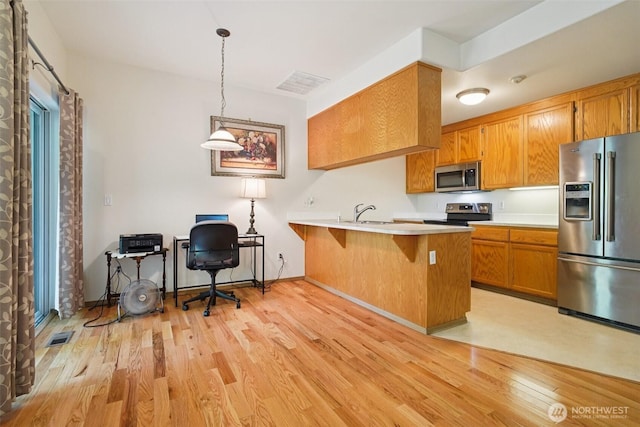 2419 S Meridian Unit B8, Puyallup, WA 98373 - kitchen featuring stainless steel appliances, light wood-type flooring, a peninsula, and brown cabinets
