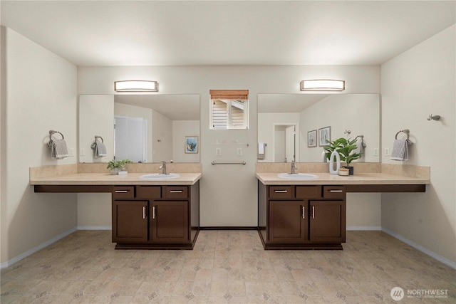 full bathroom with two vanities and baseboards