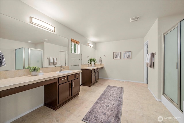 full bath featuring a stall shower, vanity, baseboards, and tile patterned floors
