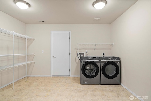 laundry area with independent washer and dryer and baseboards