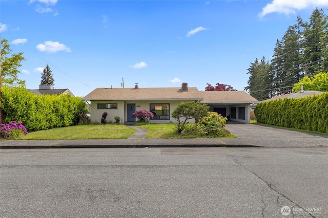 ranch-style home featuring a front yard, driveway, and a chimney