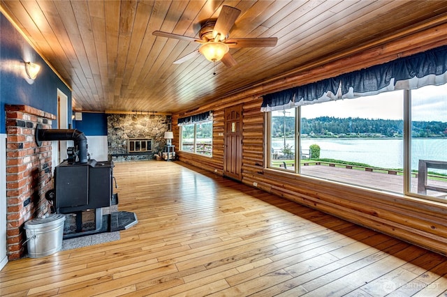 833 S Point Rd, Port Ludlow, WA 98365 - unfurnished living room with a wood stove, wood ceiling, ceiling fan, wood-type flooring, and a water view