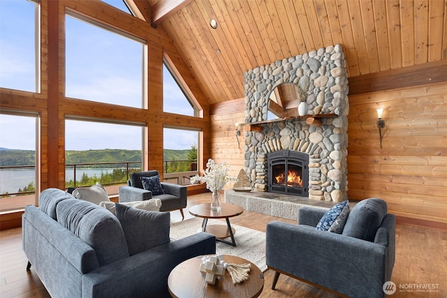 790 N Hamma Ridge Dr, Lilliwaup, WA 98555 - living area with high vaulted ceiling, a stone fireplace, wood walls, wood finished floors, and a water view