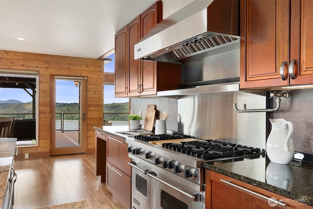 790 N Hamma Ridge Dr, Lilliwaup, WA 98555 - kitchen with double oven range, wall chimney range hood, light wood-style flooring, dark stone counters, and tasteful backsplash
