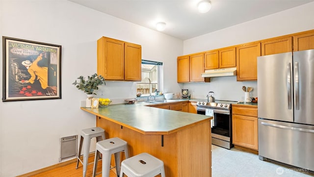 6508 NE Plum St, Suquamish, WA 98392 - kitchen featuring stainless steel appliances, under cabinet range hood, a peninsula, a breakfast bar area, and brown cabinetry