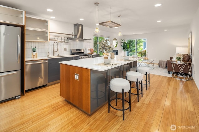1833 27th Ave, Seattle, WA 98122 - kitchen featuring stainless steel appliances, island range hood, a sink, light wood finished floors, and a breakfast bar area