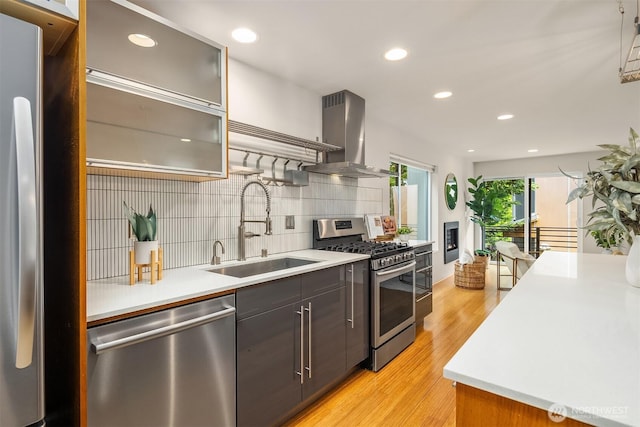 1833 27th Ave, Seattle, WA 98122 - kitchen featuring stainless steel appliances, a sink, island exhaust hood, light wood-type flooring, and decorative backsplash