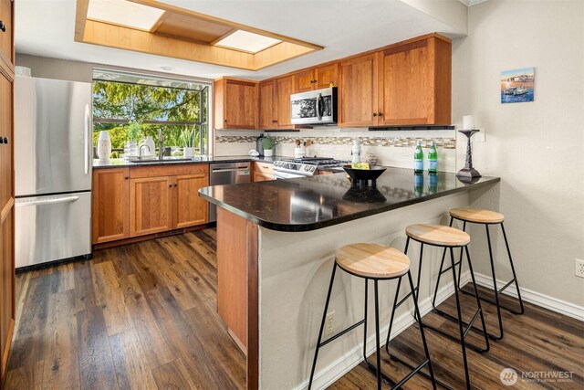 3716 Lake Washington Blvd SE Unit C, Bellevue, WA 98006 - kitchen with appliances with stainless steel finishes, decorative backsplash, a peninsula, brown cabinets, and a sink