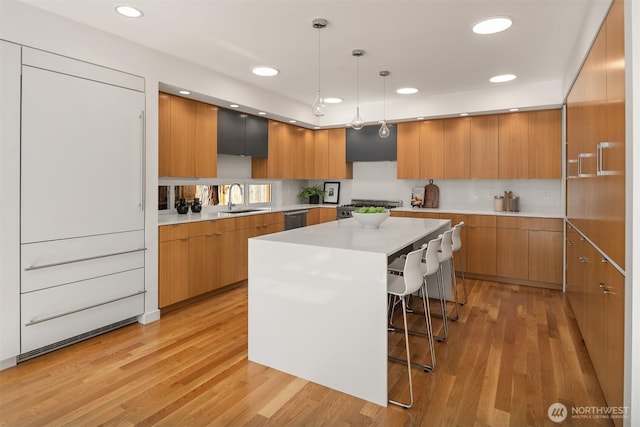 5802 43rd Ave NE, Seattle, WA 98105 - kitchen featuring modern cabinets, a sink, a breakfast bar, light wood-style flooring, and light countertops