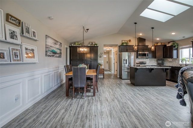184 S Razor Clam Dr SW, Ocean Shores, WA 98569 - dining area with wood finished floors, a skylight, vaulted ceiling, a chandelier, and a wainscoted wall