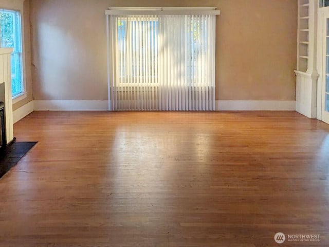 603 2nd St NW, Puyallup, WA 98371 - spare room featuring baseboards, wood finished floors, and a fireplace with flush hearth