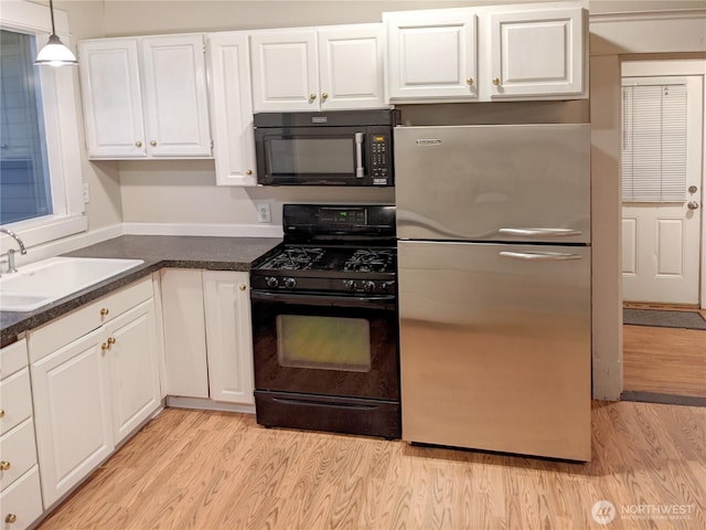 603 2nd St NW, Puyallup, WA 98371 - kitchen with black appliances, light wood-style floors, white cabinets, a sink, and dark countertops
