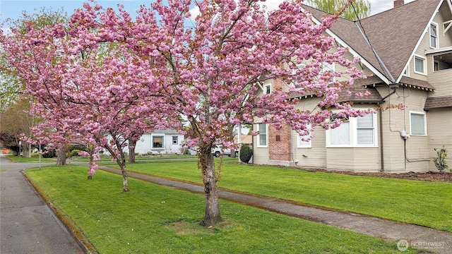 603 2nd St NW, Puyallup, WA 98371 - view of property exterior featuring a shingled roof, a lawn, and a chimney