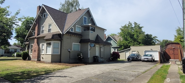603 2nd St NW, Puyallup, WA 98371 - view of front of home with an outbuilding, driveway, a chimney, a garage, and a shingled roof