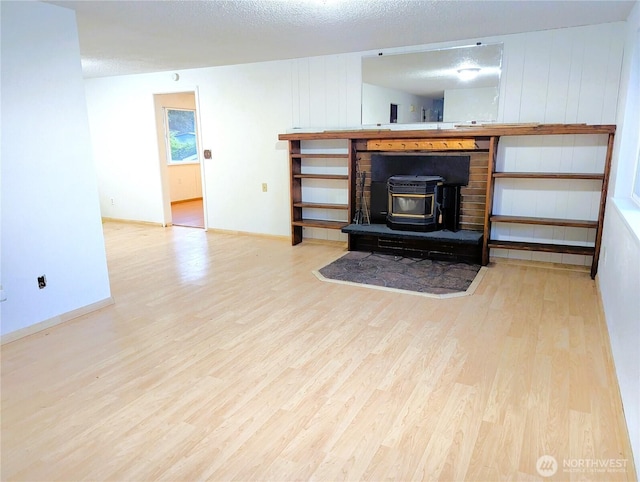 8927 178th Ave SW, Rochester, WA 98579 - unfurnished living room with wood finished floors, a wood stove, baseboards, and a textured ceiling