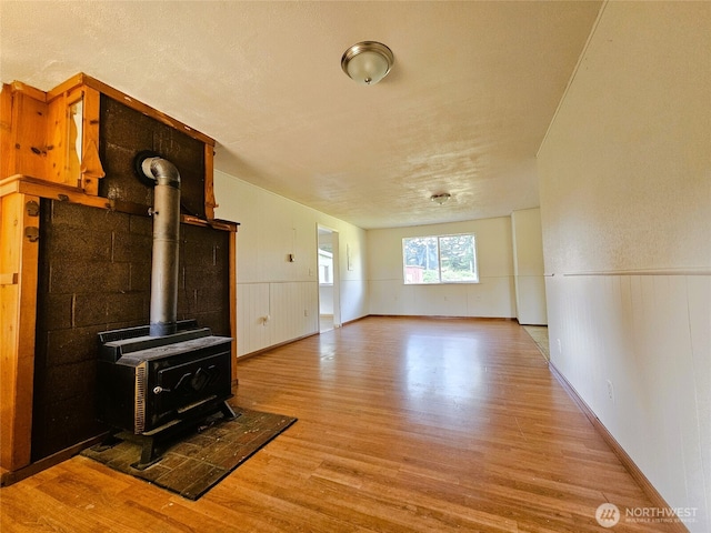 8927 178th Ave SW, Rochester, WA 98579 - unfurnished living room featuring wood finished floors, wainscoting, and a wood stove