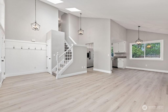 22014 48th Avenue Ct E, Spanaway, WA 98387 - unfurnished living room featuring high vaulted ceiling, light wood finished floors, stairway, baseboards, and a chandelier