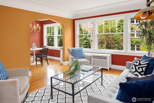 1605 E Olive St Unit 111, Seattle, WA 98122 - living area with radiator heating unit, wood finished floors, a chandelier, arched walkways, and baseboards