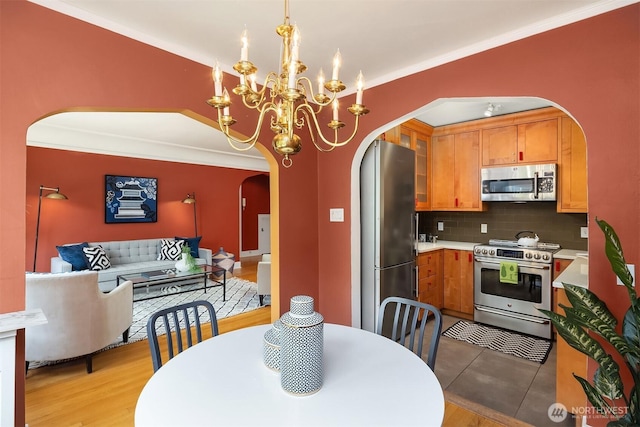 1605 E Olive St Unit 111, Seattle, WA 98122 - kitchen featuring arched walkways, appliances with stainless steel finishes, tasteful backsplash, a chandelier, and glass insert cabinets