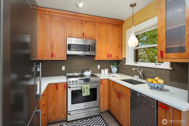 1605 E Olive St Unit 111, Seattle, WA 98122 - kitchen with appliances with stainless steel finishes, a sink, light countertops, brown cabinetry, and backsplash