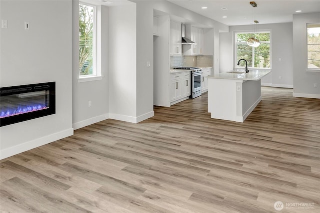 6726 NE 187th St Unit 104, Kenmore, WA 98028 - kitchen featuring stainless steel gas range oven, a sink, white cabinets, light wood-style floors, and baseboards