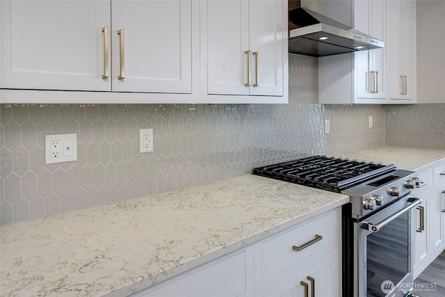 6726 NE 187th St Unit 104, Kenmore, WA 98028 - kitchen featuring stainless steel gas stove, ventilation hood, white cabinets, light stone counters, and decorative backsplash