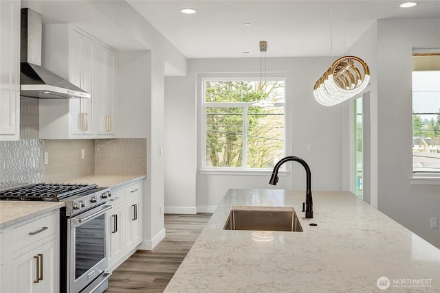 6726 NE 187th St Unit 104, Kenmore, WA 98028 - kitchen with wall chimney exhaust hood, stainless steel gas range oven, a sink, light stone counters, and tasteful backsplash