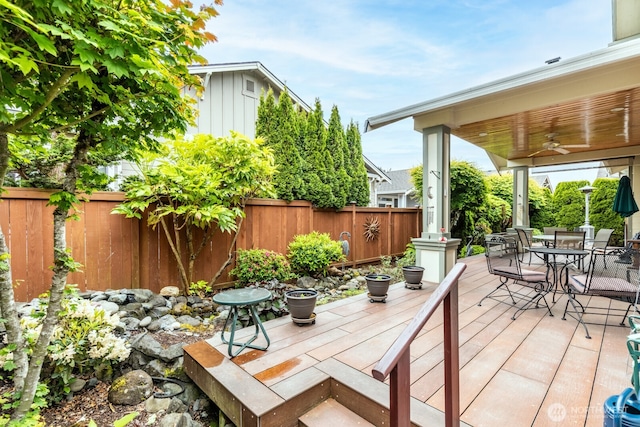 wooden terrace featuring ceiling fan, a fenced backyard, and outdoor dining area