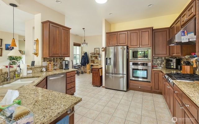 kitchen featuring stainless steel appliances, under cabinet range hood, a sink, backsplash, and light stone counters