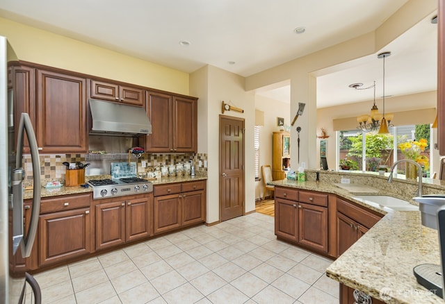 kitchen featuring under cabinet range hood, a sink, stainless steel appliances, backsplash, and light tile patterned flooring
