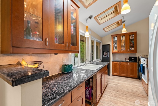 1933 Dayton Dr SE, Renton, WA 98055 - kitchen with a sink, brown cabinetry, vaulted ceiling, a skylight, and backsplash