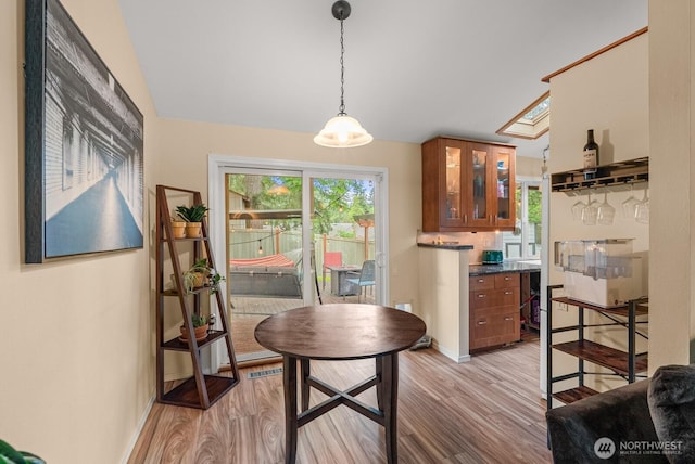1933 Dayton Dr SE, Renton, WA 98055 - kitchen featuring brown cabinets, light wood finished floors, lofted ceiling, healthy amount of natural light, and glass insert cabinets