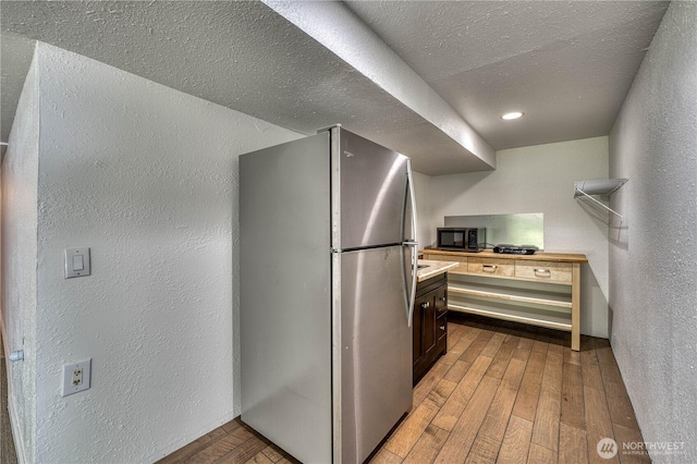 1245 SW 301st St, Federal Way, WA 98023 - kitchen with appliances with stainless steel finishes, a textured wall, hardwood / wood-style floors, a textured ceiling, and light countertops
