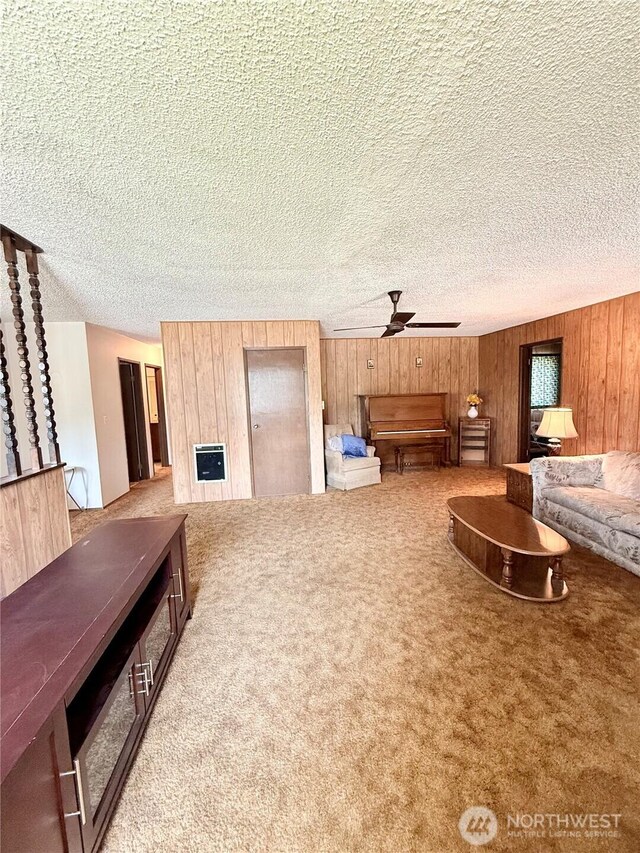 718 Ridge Pl, Omak, WA 98841 - carpeted living area with ceiling fan, wood walls, heating unit, and a textured ceiling