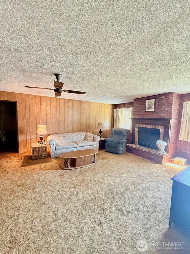 718 Ridge Pl, Omak, WA 98841 - carpeted living room with a textured ceiling, wood walls, a ceiling fan, and a brick fireplace