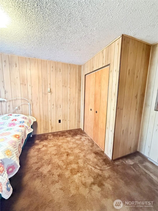 718 Ridge Pl, Omak, WA 98841 - bedroom with a textured ceiling, carpet flooring, wood walls, and a closet