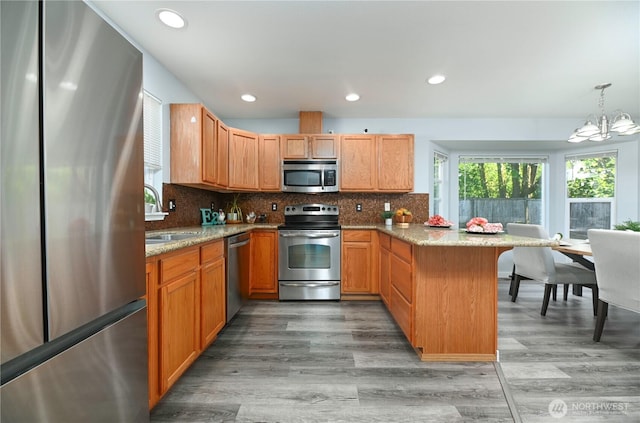 1416 116th Dr SE, Lake Stevens, WA 98258 - kitchen featuring appliances with stainless steel finishes, a peninsula, a sink, a chandelier, and light wood-style floors