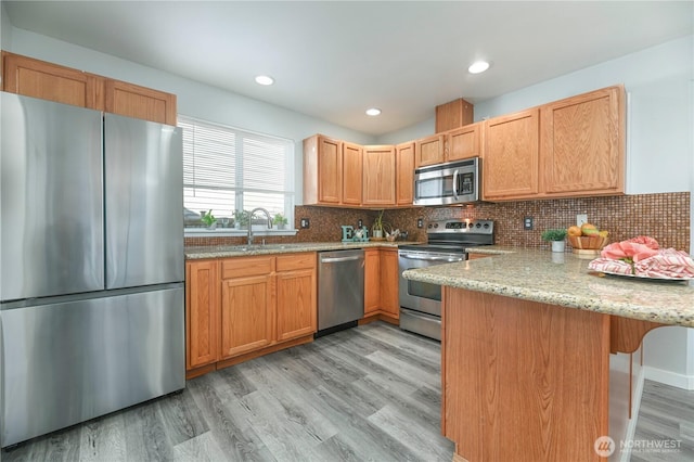 1416 116th Dr SE, Lake Stevens, WA 98258 - kitchen with appliances with stainless steel finishes, a peninsula, a sink, light stone countertops, and light wood-style floors