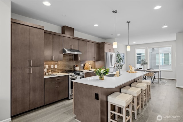 7629 NE 122nd Ct Unit 7, Kirkland, WA 98034 - kitchen featuring stainless steel appliances, a breakfast bar area, light wood-style flooring, light countertops, and a center island with sink