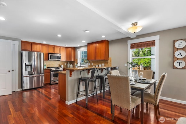 830 15th Ave Unit A, Seattle, WA 98122 - kitchen with appliances with stainless steel finishes, dark wood-type flooring, backsplash, a peninsula, and brown cabinetry