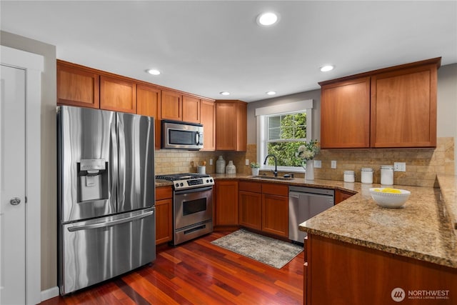 830 15th Ave Unit A, Seattle, WA 98122 - kitchen featuring appliances with stainless steel finishes, a sink, brown cabinetry, dark wood-type flooring, and light stone countertops