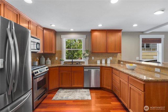 830 15th Ave Unit A, Seattle, WA 98122 - kitchen featuring stainless steel appliances, a sink, light wood-style flooring, a peninsula, and decorative backsplash
