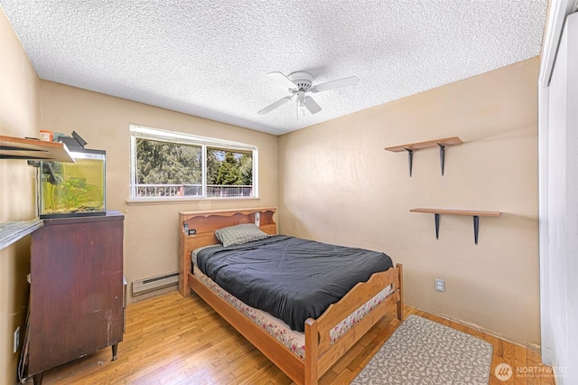 2 Quinault Way, La Conner, WA 98257 - bedroom featuring a baseboard heating unit, wood finished floors, a textured ceiling, and a ceiling fan