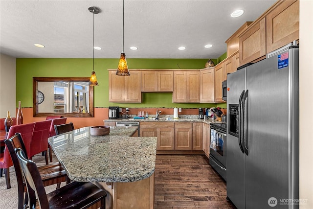 9159 Riverview Way NW Unit D39, Quincy, WA 98848 - kitchen featuring appliances with stainless steel finishes, light stone counters, dark wood finished floors, recessed lighting, and a kitchen bar