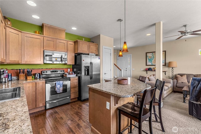 9159 Riverview Way NW Unit D39, Quincy, WA 98848 - kitchen with appliances with stainless steel finishes, open floor plan, a kitchen island, dark wood-style floors, and a breakfast bar