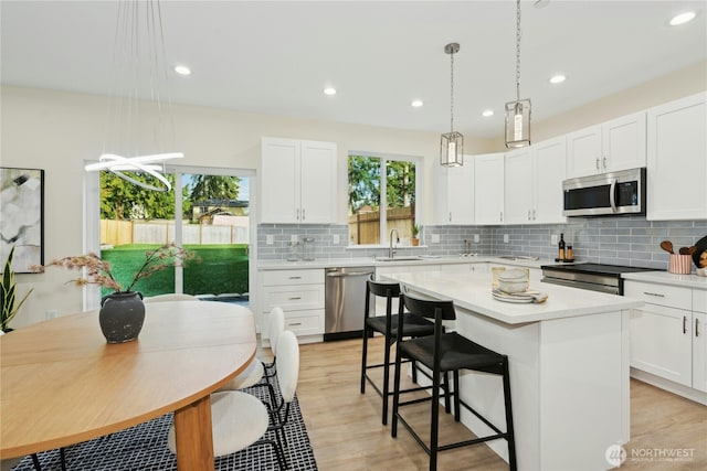 121 120th St SE Unit B, Everett, WA 98208 - kitchen with stainless steel appliances, light countertops, a center island, a breakfast bar, and recessed lighting