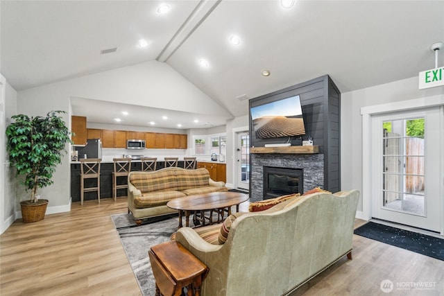 15150 140th Way SE Unit T304, Renton, WA 98058 - living room featuring light wood finished floors, a stone fireplace, plenty of natural light, high vaulted ceiling, and recessed lighting