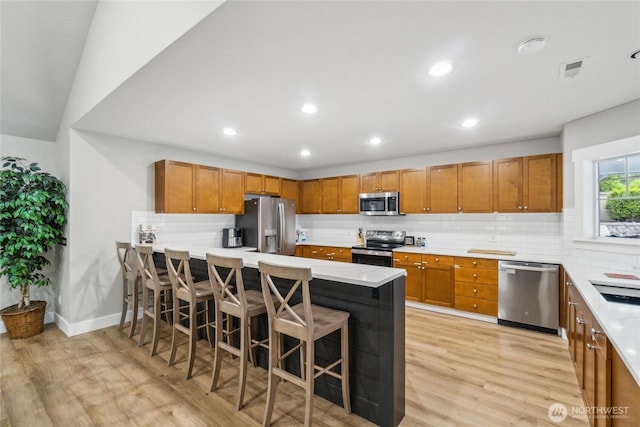 15150 140th Way SE Unit T304, Renton, WA 98058 - kitchen with stainless steel appliances, light wood-type flooring, brown cabinets, a breakfast bar, and recessed lighting